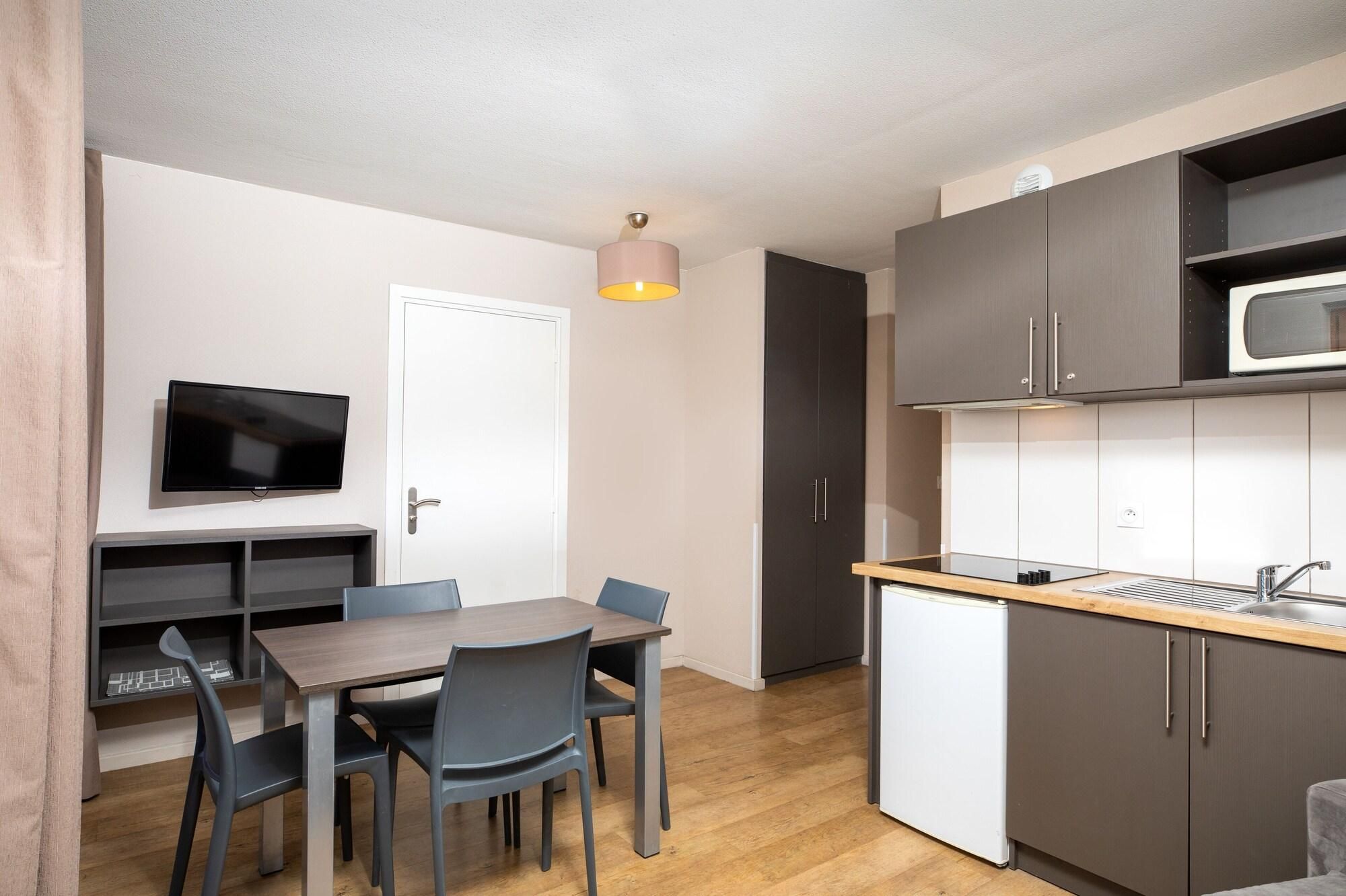 Una cocina compacta con microondas, lavabo y zona de comedor con mesa y sillas.