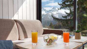Una mesa de madera con dos vasos de zumo de naranja y un bol de aceitunas.