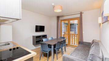 A compact living space with a kitchenette, dining area, and a sofa.