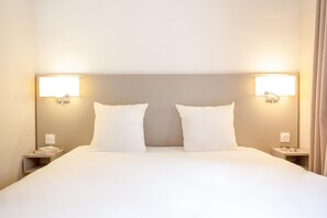 A hotel room with a large bed, two bedside tables, and wall-mounted lamps. - Sowell Residences Pra Loup (Uvernet-Fours)