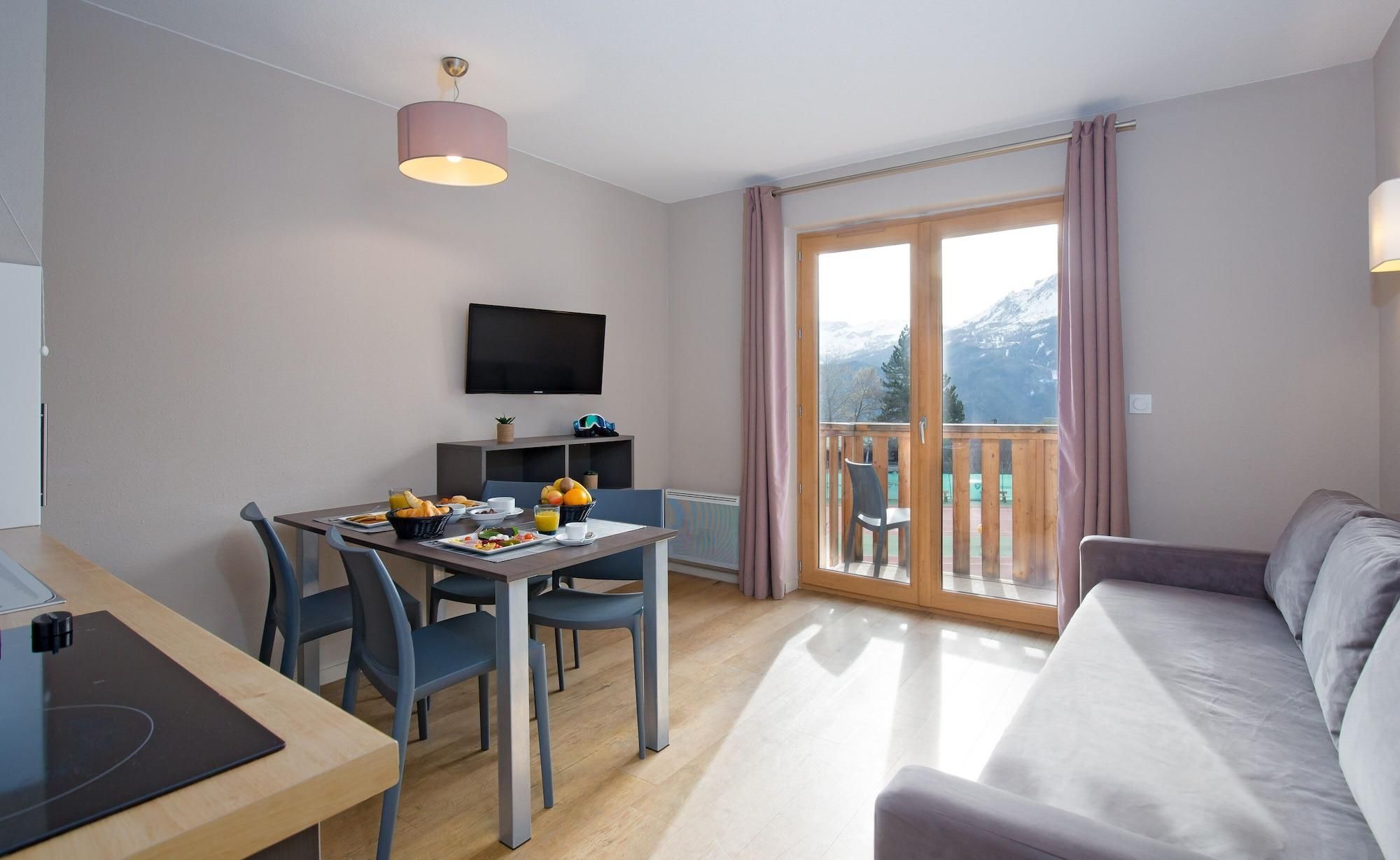 Een moderne woonkamer met een eetgedeelte, een flatscreen televisie en een balkon met uitzicht op de bergen.