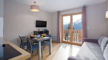Een moderne woonkamer met een eetgedeelte, een flatscreen televisie en een balkon met uitzicht op de bergen.