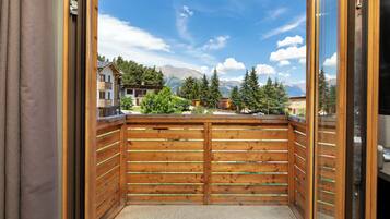 Un balcon en bois offrant une vue sur les montagnes et les bâtiments.