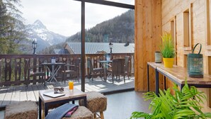 A wooden deck with outdoor seating, a view of mountains, and a wooden cabin structure. - Sowell Residences Pra Loup (Uvernet-Fours)
