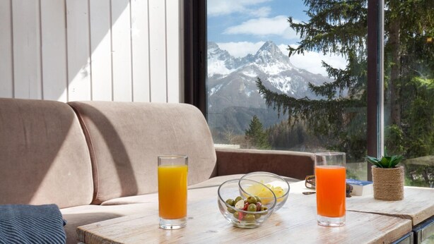 A wooden table with two glasses of orange juice and a bowl of olives. - Sowell Residences Pra Loup (Uvernet-Fours)