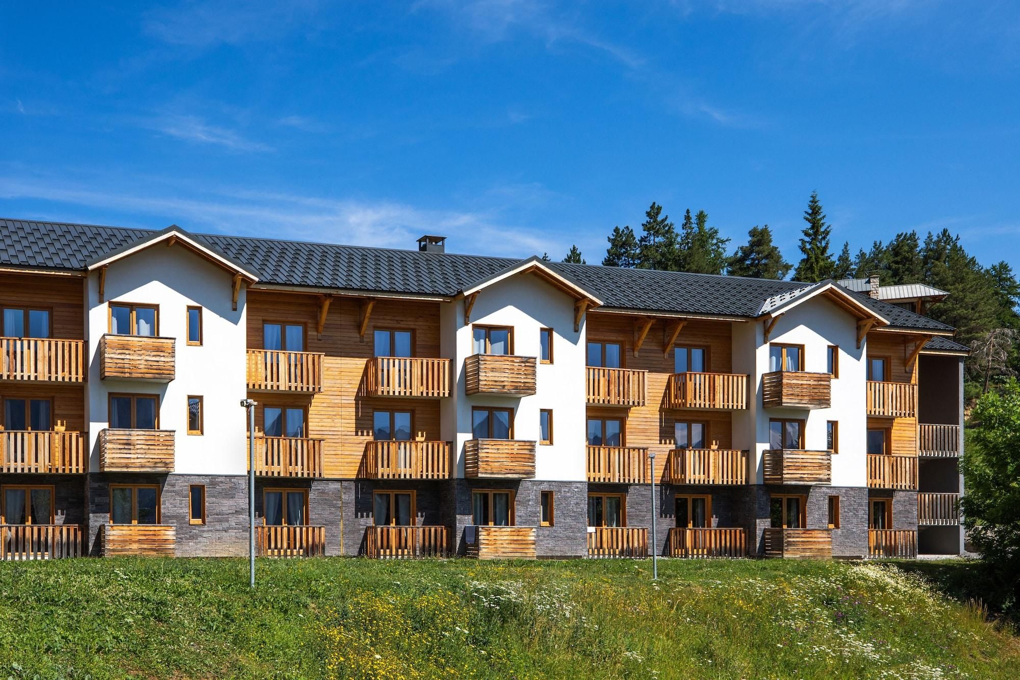 Ett hotell med flera våningar, träbalkonger och detaljer i sten.