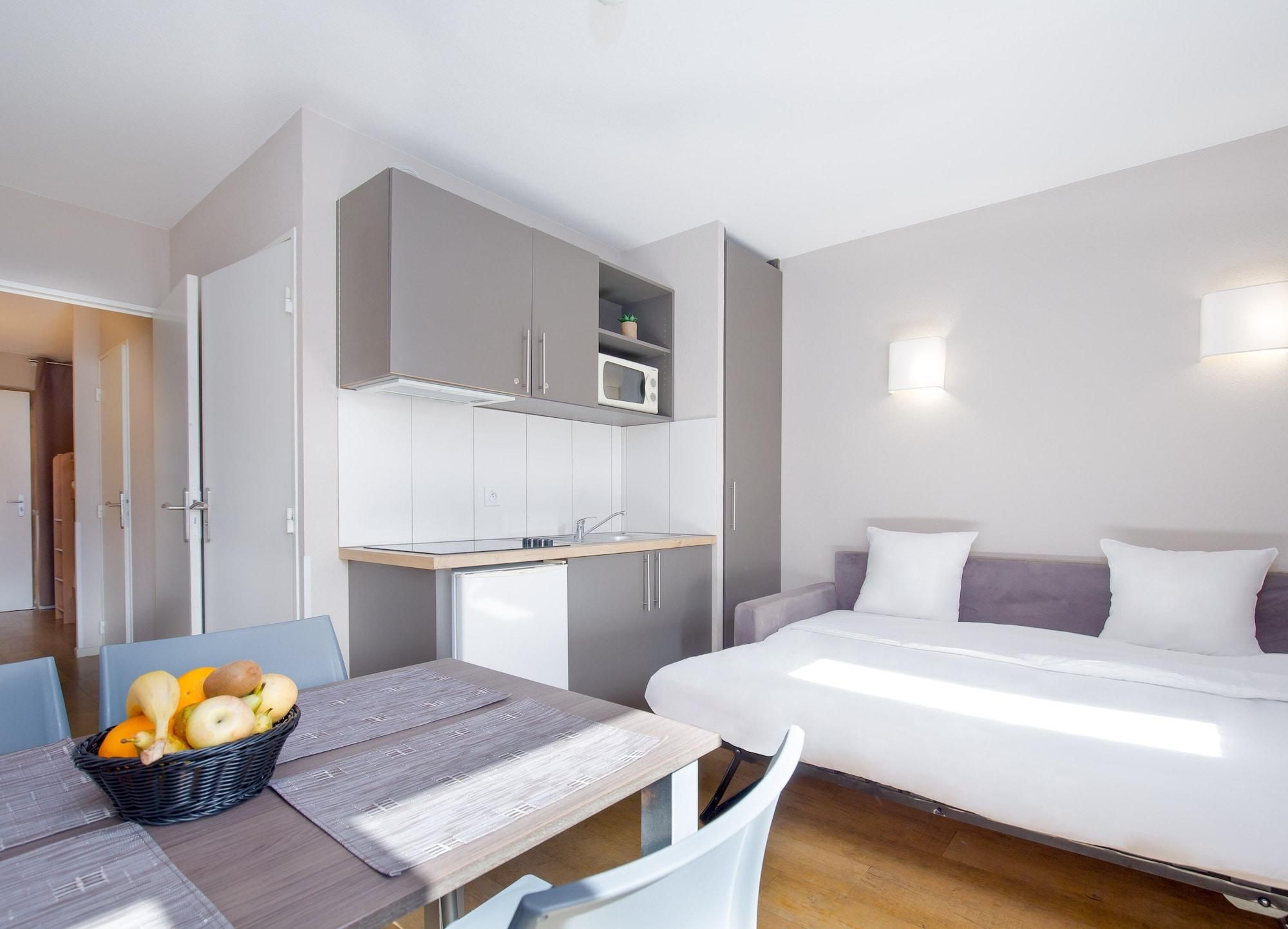 Una habitación de hotel compacta con kitchenette, una cama y un comedor.
