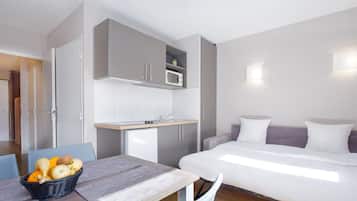Une chambre d’hôtel compacte comprenant un coin cuisine, un lit et un espace repas.