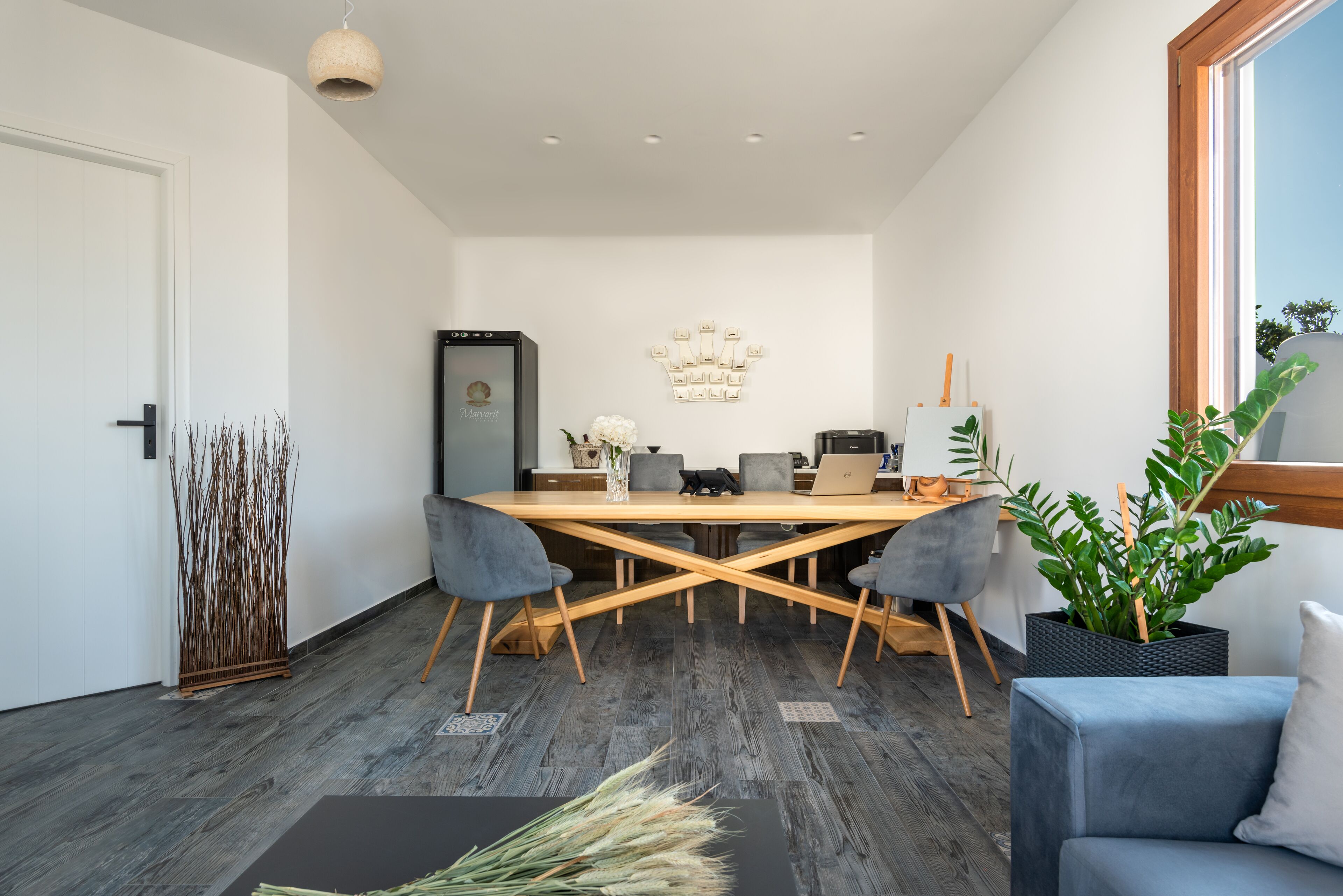 Un comedor moderno con una mesa de madera, sillas grises y un ordenador portátil sobre la mesa.