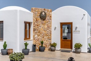 A building with a stone wall, a reception area, and potted plants.