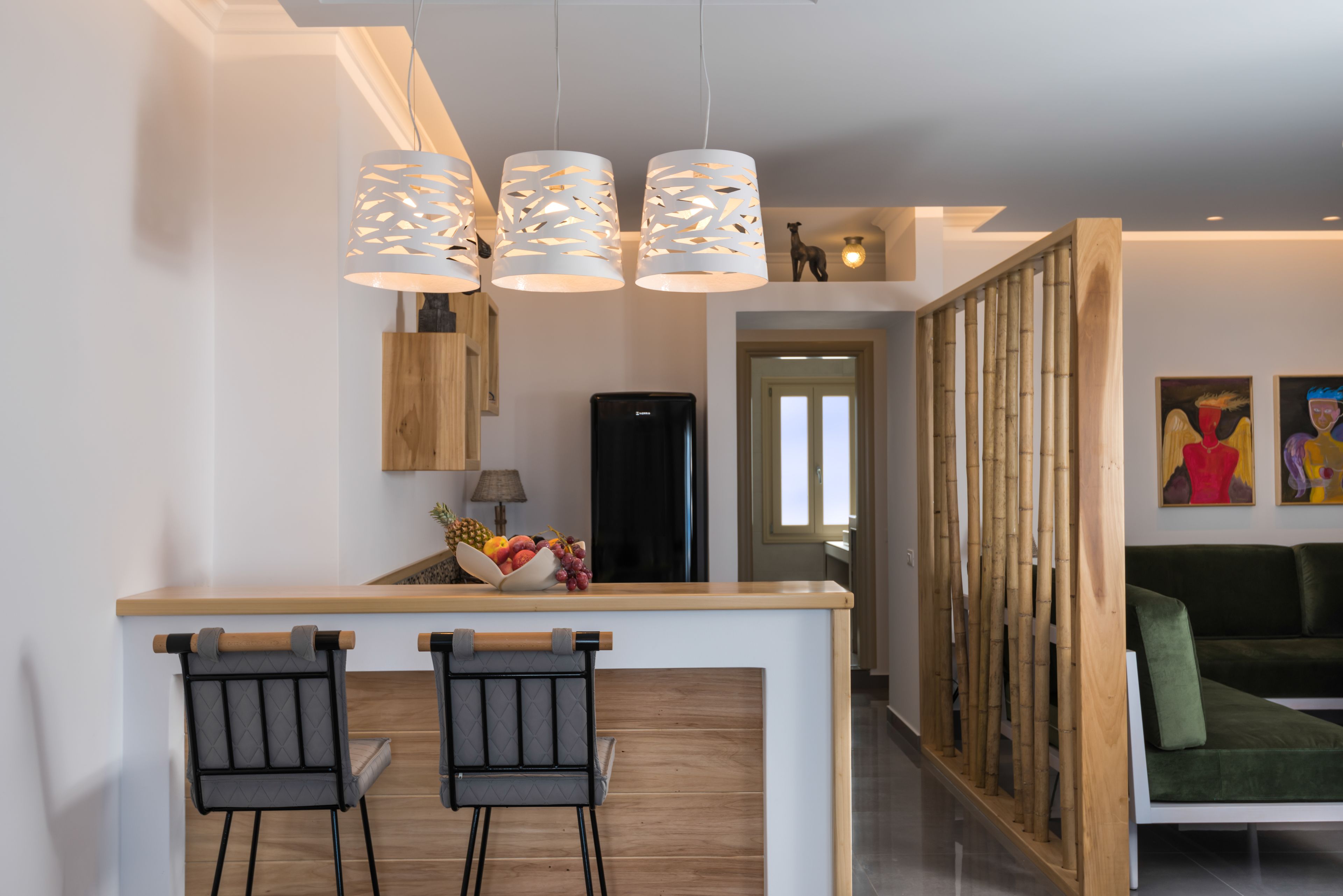 A modern kitchen with a wooden island, two bar stools, and a fruit bowl.