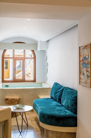A modern living room with a curved teal sofa, a round coffee table, and a large arched window.