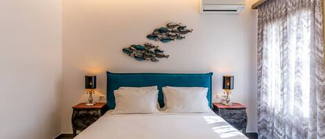 A neatly made bed with white linens, a teal headboard, and two bedside lamps.