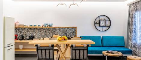 A modern kitchen with a dining table, chairs, and a blue sofa.
