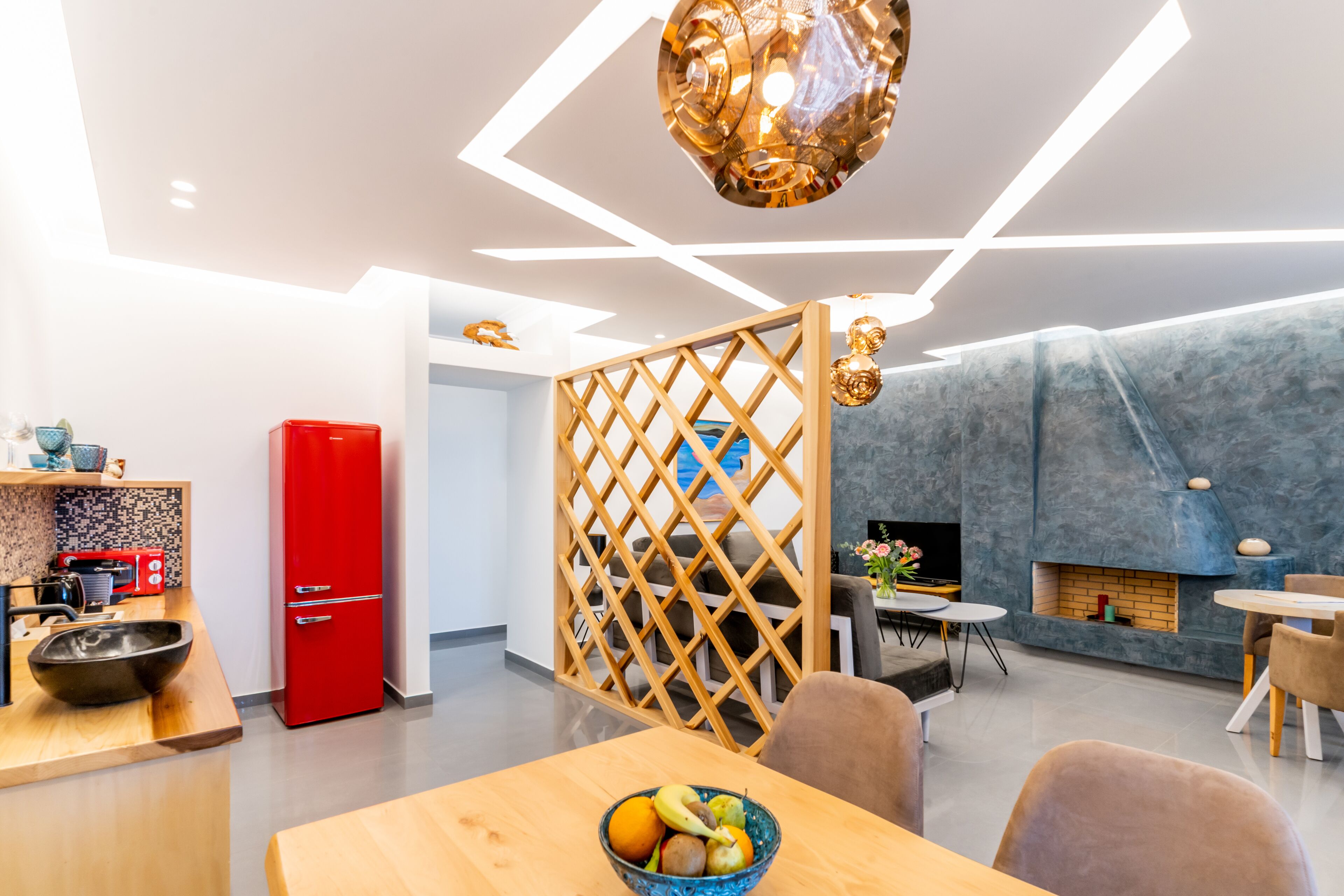 Una cocina moderna con un refrigerador rojo, separador de madera y un comedor con mesa y sillas.