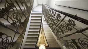 A staircase with ornate metal railings and a light fixture at the bottom. - Letna Garden Suites (Prague)