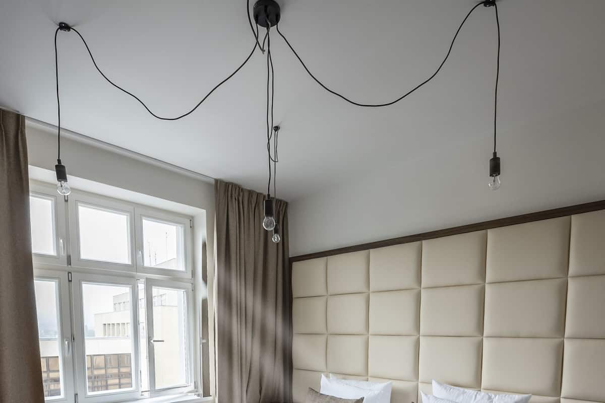 Una camera da letto con un grande letto, una testiera, una finestra con tende e un pavimento in legno.