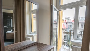 A modern bathroom with a large mirror, wooden vanity, and a view of the outside balcony. - Letna Garden Suites (Prague)