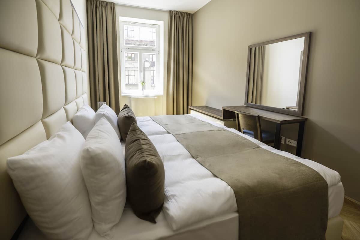 Una camera d'albergo con un letto grande, una scrivania, una sedia e uno specchio ampio.