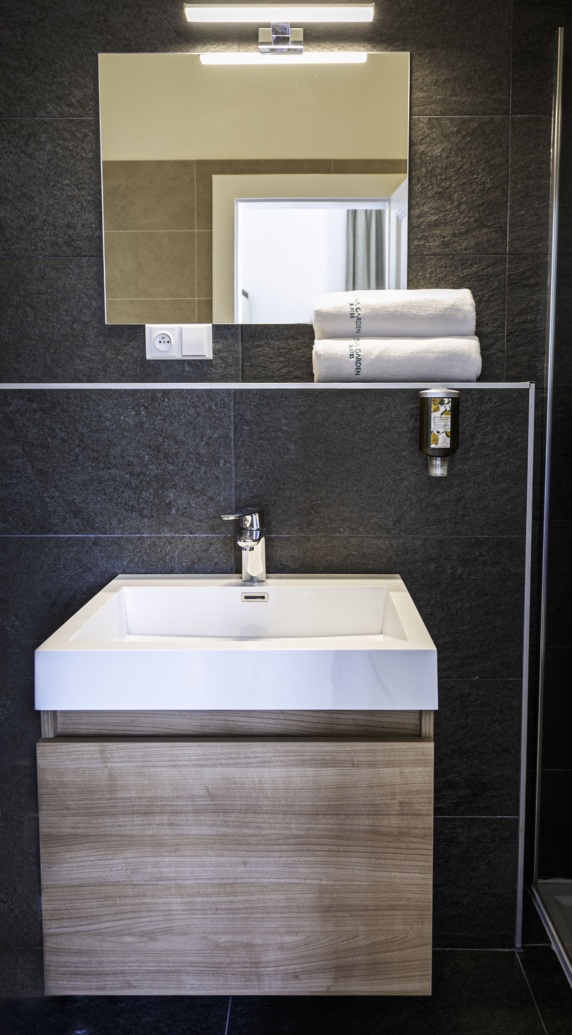 Un baño moderno con un lavamanos grande, un espejo y un perchero para toallas.