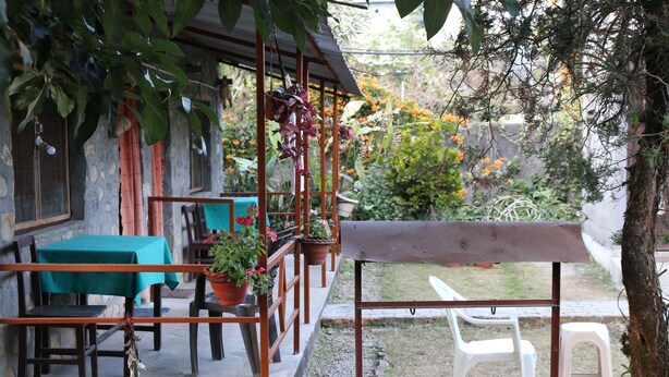 A patio area with tables and chairs, potted plants, and a view of the surrounding garden. - Gurkha Lodge (Pokhara)