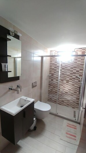 Apartamento | Banheiro | Chuveiro com efeito de chuva, secador de cabelo, toalhas de banho 