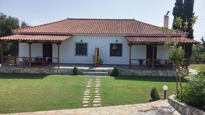 A two-story house with a tiled roof, a stone foundation, and a well-maintained lawn. - Dora Apartments (Zakynthos)