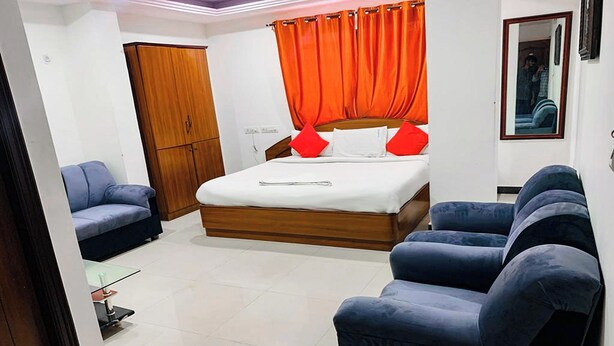 A hotel room with a bed, two sofas, a wardrobe, and a mirror. - Hotel Champion Inn near Yeswantpur Junction Railway Station (Bengaluru)