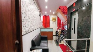 A hotel lobby with a reception desk, a black leather sofa, a red carpet, and a staircase with a red railing. - Hotel Champion Inn near Yeswantpur Junction Railway Station (Bengaluru)