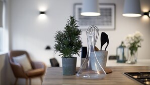 A modern kitchen with a wooden table, a potted plant, a clear glass vase with utensils, and pendant lights. - Apartment T10c (Reykjavik)