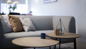 A modern living room with a grey sofa, two round tables, and a decorative metal sculpture. - Apartment T10c (Reykjavik)