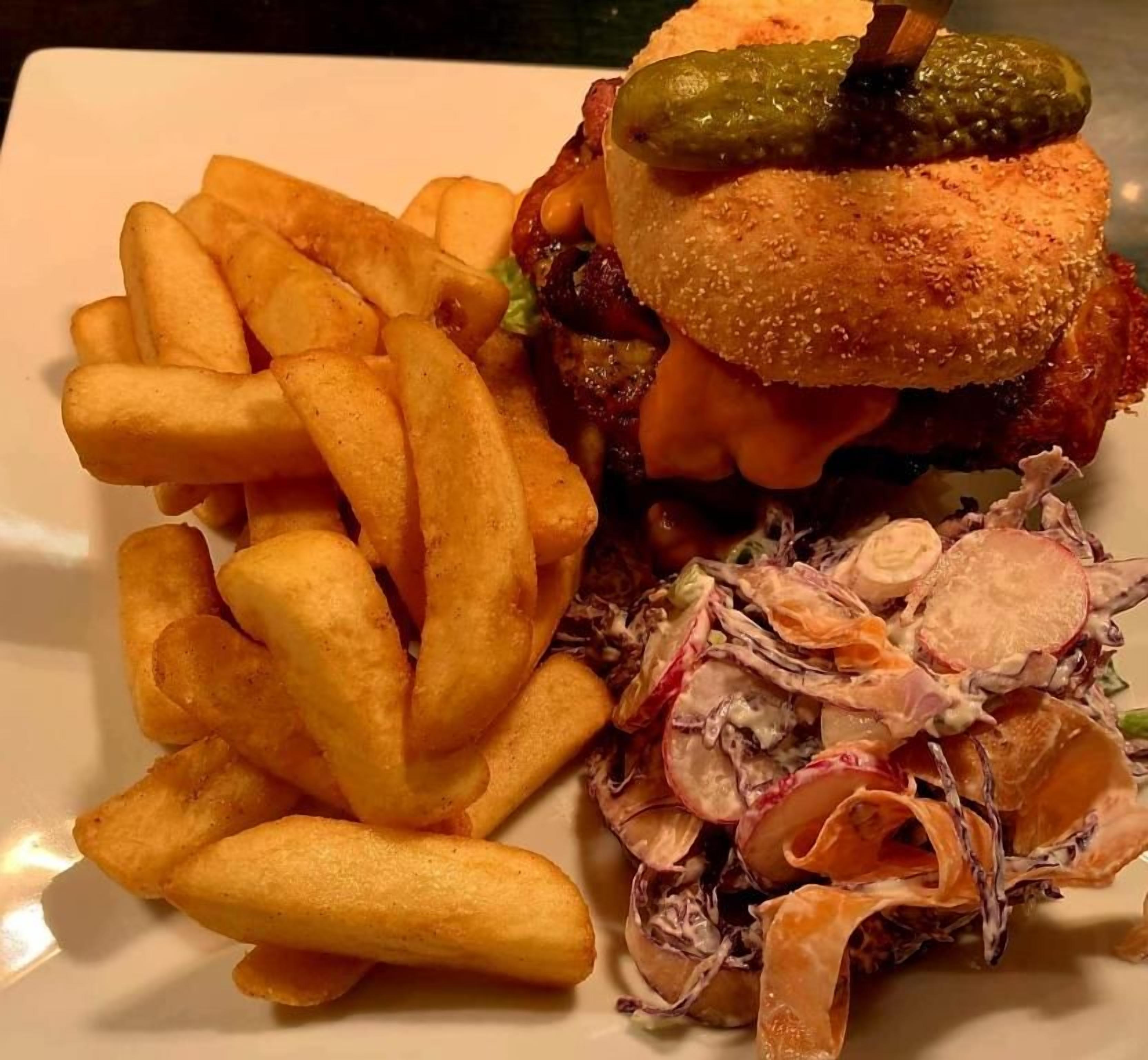 Un piatto con un hamburger, patatine fritte e insalata di cavolo.