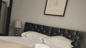 A neatly made bed with white linens and a folded towel, a bedside lamp, and a framed picture on the wall. - The Black Lion Royal Hotel (Lampeter)