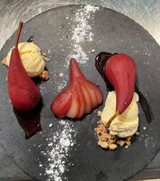Um prato de sobremesa com bolas de sorvete em formato de pera e calda de chocolate.