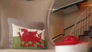 A sofa with a cushion featuring a red dragon design, a staircase, and a dessert on a table. - The Black Lion Royal Hotel (Lampeter)