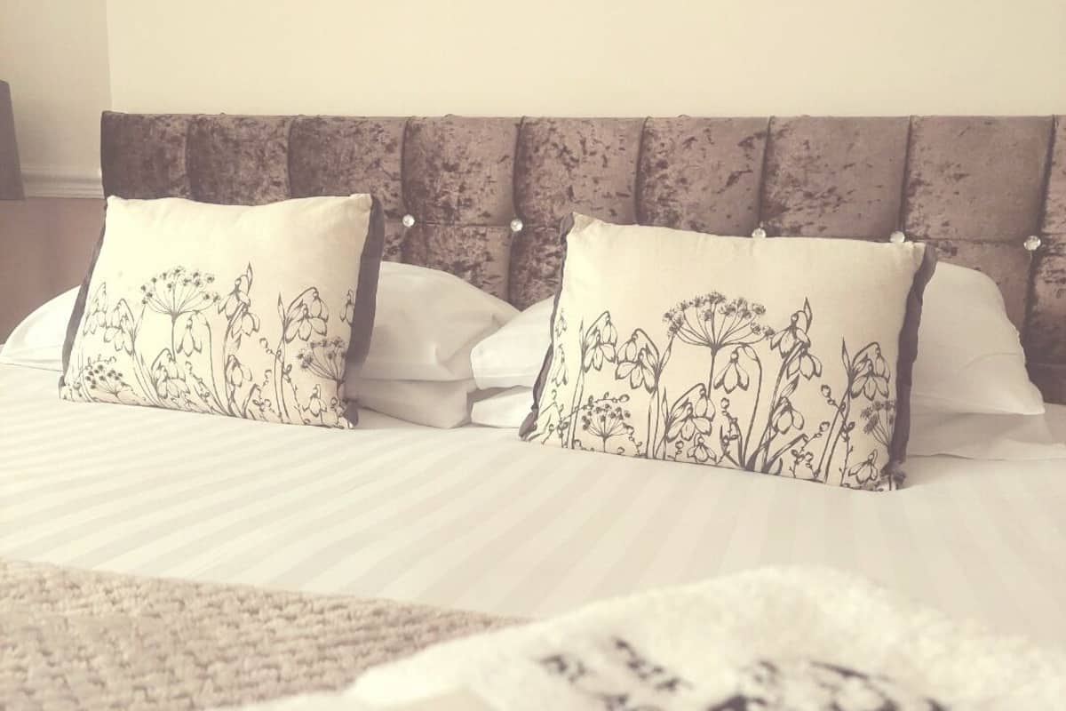A neatly made bed with floral-patterned pillows and a white comforter.