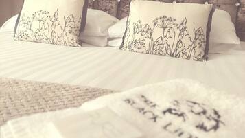 A neatly made bed with floral-patterned pillows and a white comforter.