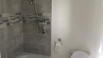 Une salle de bain équipée d’une baignoire, d’une douche, de toilettes et d’une poubelle.
