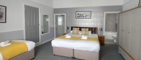 Ein Hotelzimmer mit einem großen Bett, zwei Nachttischen, einem Kleiderschrank, einem Badezimmer mit Badewanne und Toilette sowie einem Kronleuchter.