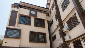 A multi-story building with a beige facade, multiple windows with metal bars, and air conditioning units mounted on the exterior walls.