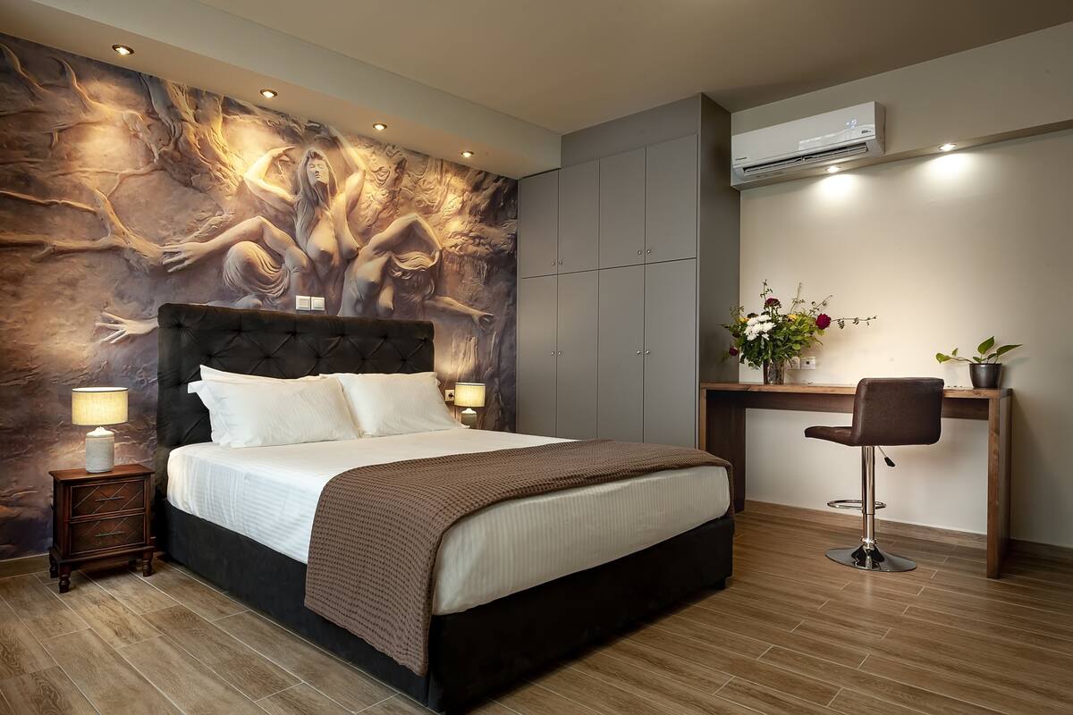 Een moderne slaapkamer met een groot bed, een bureau, een stoel en een wanddecoratie.