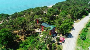 An aerial view of a coastal property with a red building, a beach, and dense greenery. - New Wave (Grigoleti)