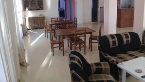 A spacious living area with a dining table, multiple chairs, a sofa, and a television. - New Wave (Grigoleti)