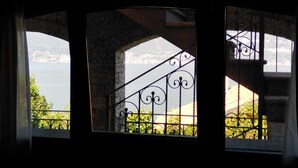A room with a view of a lake through a window with a wrought iron railing.