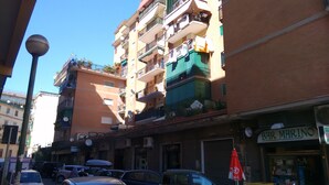 A multi-story building with balconies, a visible storefront, and parked cars. - Turist Rent Apartment Nadia (Napoli)