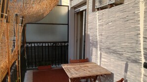 A small outdoor patio with a wooden table and chairs, a woven shade, and a metal fence. - Turist Rent Apartment Nadia (Napoli)