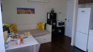 A compact kitchen with a refrigerator, microwave, and a small dining area with a table set for breakfast. - Turist Rent Apartment Nadia (Napoli)