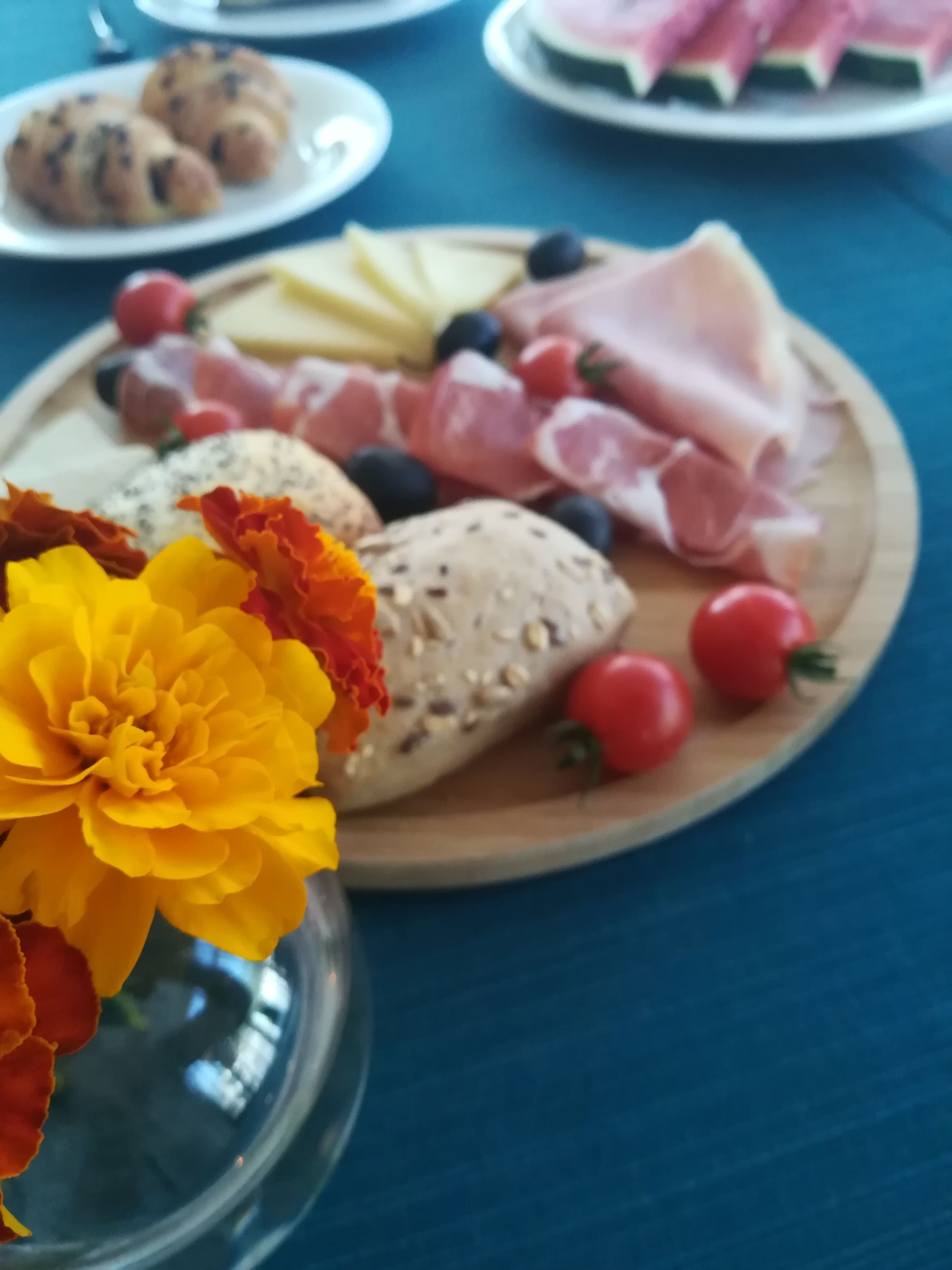 Una mesa con diversos alimentos, incluyendo pan, queso, tomates y flores.