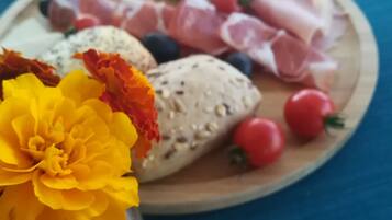 Una mesa con diversos alimentos, incluyendo pan, queso, tomates y flores.