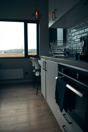 Una cocina moderna con un ventanal grande, suelo de madera y vistas a un paisaje rural.